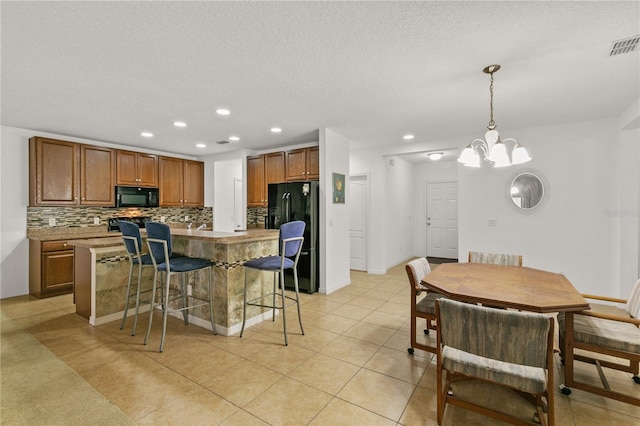 kitchen featuring a breakfast bar, a center island, backsplash, brown cabinetry, and black appliances