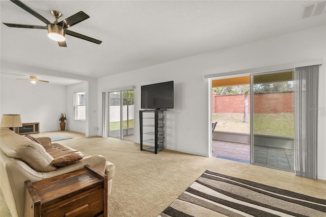 carpeted living area with a ceiling fan, visible vents, and a textured ceiling