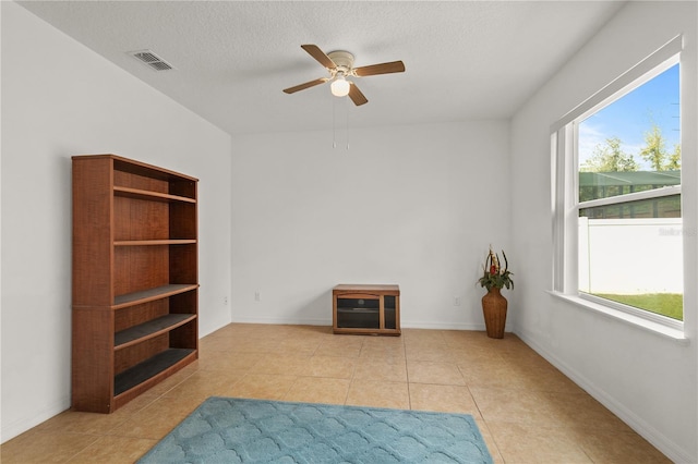 living area with a wealth of natural light, visible vents, a textured ceiling, and tile patterned floors