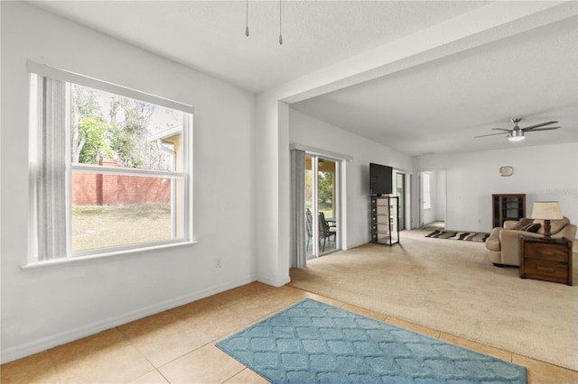 interior space featuring ceiling fan, a textured ceiling, tile patterned flooring, and baseboards