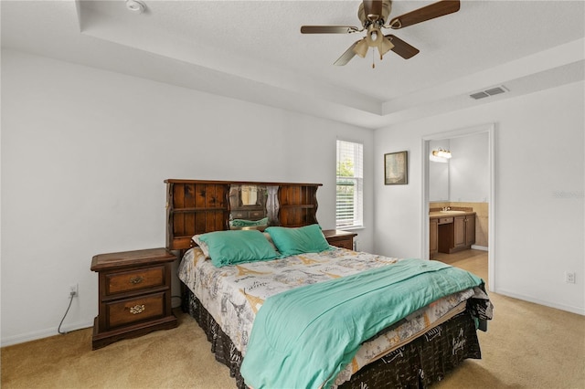 bedroom featuring a tray ceiling, carpet, a sink, and visible vents