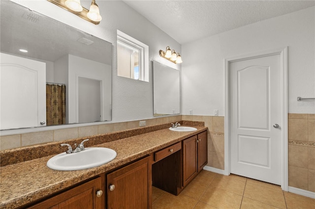 bathroom featuring double vanity, tile walls, tile patterned floors, a textured ceiling, and a sink