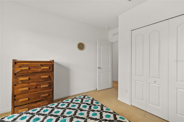 bedroom with baseboards, visible vents, a closet, and light colored carpet