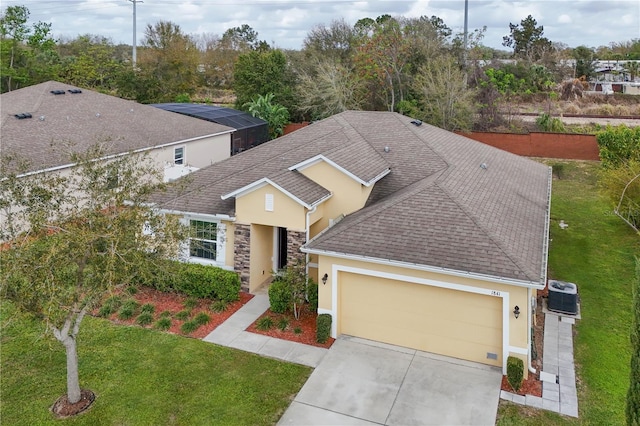 view of front of house with central air condition unit, a shingled roof, an attached garage, and concrete driveway