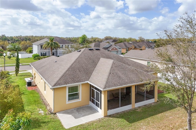 back of property with stucco siding, a shingled roof, a lawn, a sunroom, and central AC