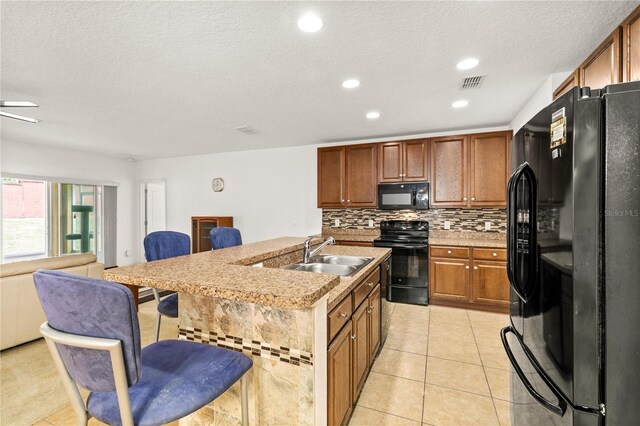 1841 Dunn Cove Dr, Apopka, FL 32703 - kitchen featuring a breakfast bar, a sink, open floor plan, black appliances, and backsplash