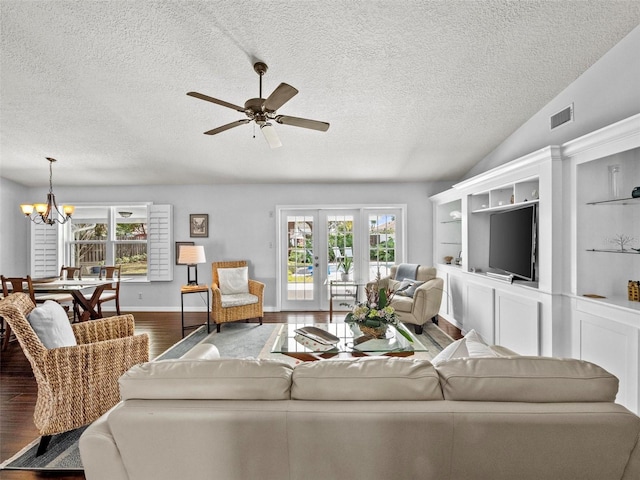 living area with visible vents, lofted ceiling, wood finished floors, a textured ceiling, and ceiling fan with notable chandelier