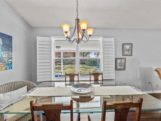 dining area featuring baseboards, a chandelier, and a textured ceiling