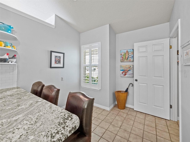 dining area with lofted ceiling, light tile patterned flooring, a textured ceiling, and baseboards