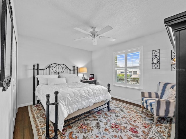 bedroom featuring a textured ceiling, ceiling fan, wood finished floors, and baseboards