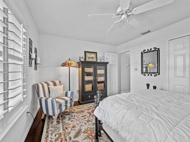 bedroom featuring visible vents, ceiling fan, baseboards, and wood finished floors