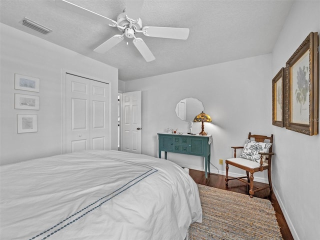 bedroom with a closet, visible vents, a ceiling fan, wood finished floors, and baseboards