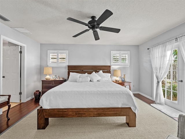 bedroom featuring wood finished floors, a ceiling fan, baseboards, visible vents, and access to exterior