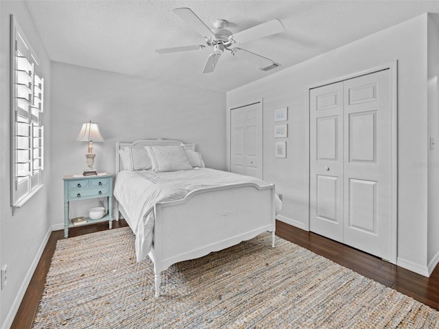 bedroom with dark wood-type flooring, visible vents, multiple windows, and two closets