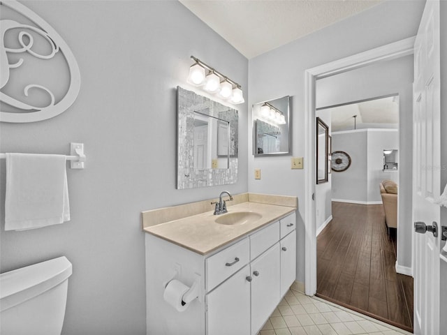 bathroom with baseboards, toilet, tile patterned flooring, a textured ceiling, and vanity