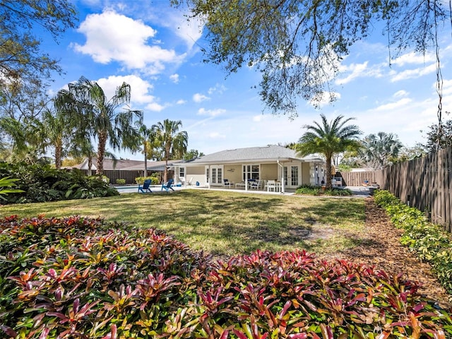 view of yard featuring a patio area, a fenced backyard, a swimming pool, and french doors