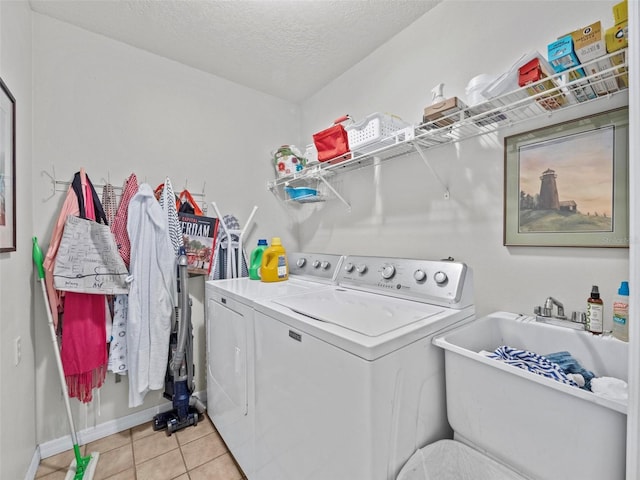 laundry room with washer and clothes dryer, light tile patterned floors, a sink, a textured ceiling, and laundry area