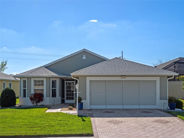 single story home featuring decorative driveway, roof with shingles, stucco siding, an attached garage, and a front yard