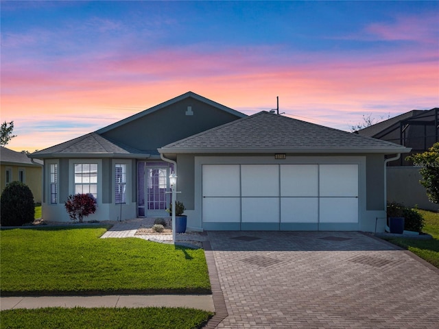 single story home featuring a garage, roof with shingles, decorative driveway, a front lawn, and stucco siding