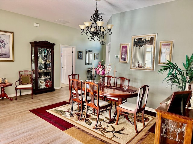 dining space featuring visible vents, an inviting chandelier, baseboards, and wood finished floors