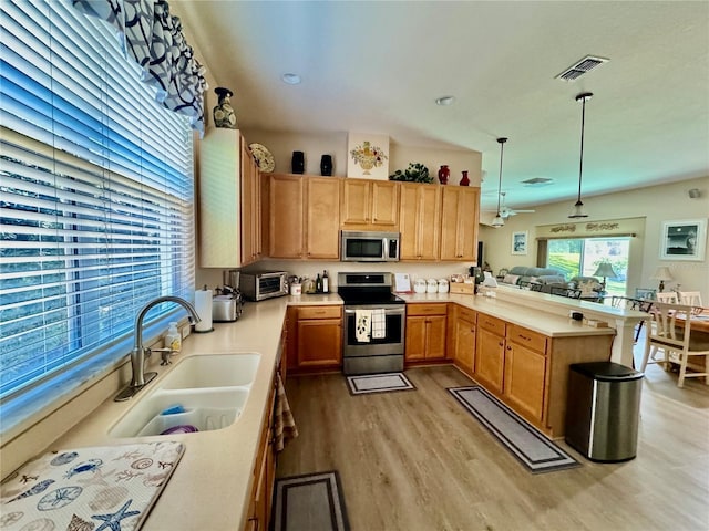 kitchen with visible vents, a sink, light wood-style floors, appliances with stainless steel finishes, and a peninsula