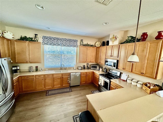 kitchen with a sink, light countertops, light wood finished floors, and stainless steel appliances