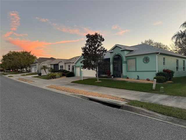 view of front facade featuring concrete driveway, a lawn, a garage, and stucco siding