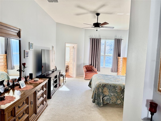 carpeted bedroom with ensuite bath, visible vents, and ceiling fan