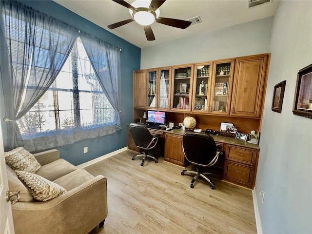 home office featuring visible vents, baseboards, light wood-style flooring, and built in desk