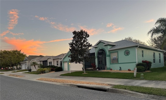 view of front facade featuring a lawn, an attached garage, concrete driveway, and stucco siding