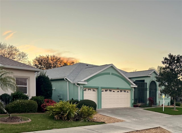 ranch-style home with stucco siding, a yard, concrete driveway, and an attached garage