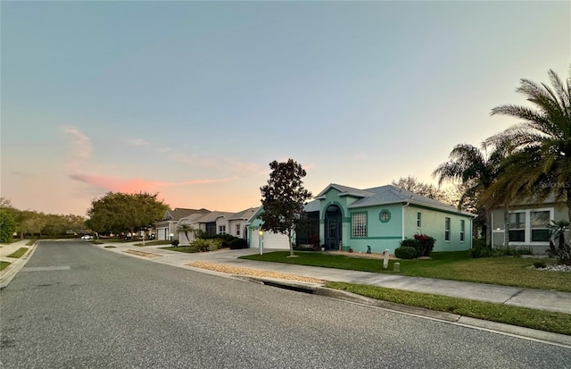 view of front of home featuring concrete driveway, a lawn, a residential view, and stucco siding