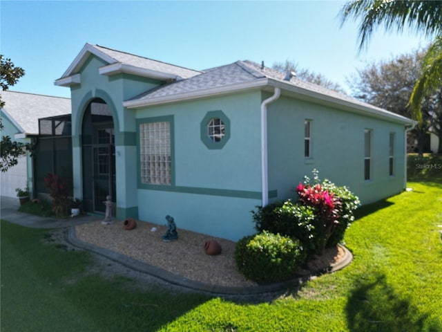 exterior space with a shingled roof, a yard, a garage, and stucco siding