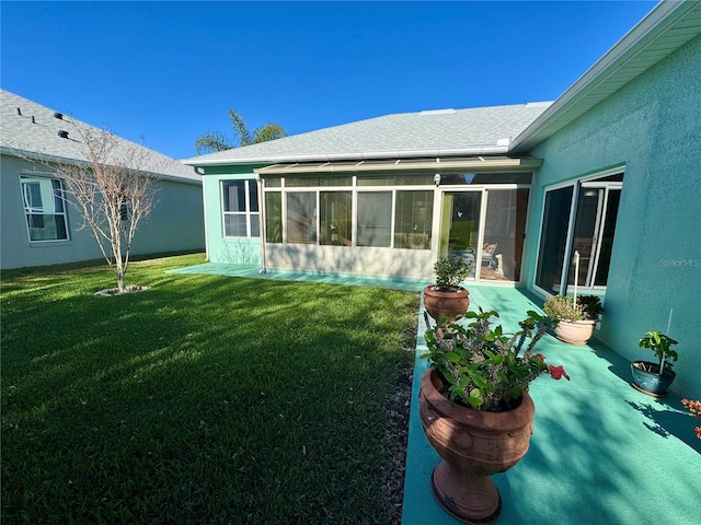 rear view of house featuring stucco siding, a lawn, roof with shingles, and a sunroom