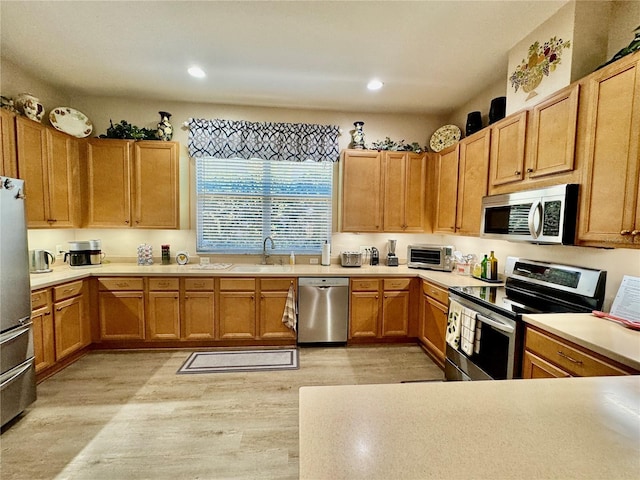 kitchen featuring light wood-style flooring, a toaster, recessed lighting, and appliances with stainless steel finishes