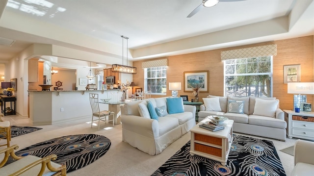 living area with ceiling fan, wooden walls, and light colored carpet