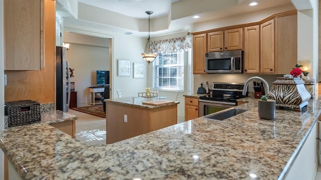 kitchen featuring a center island, recessed lighting, hanging light fixtures, appliances with stainless steel finishes, and light stone countertops