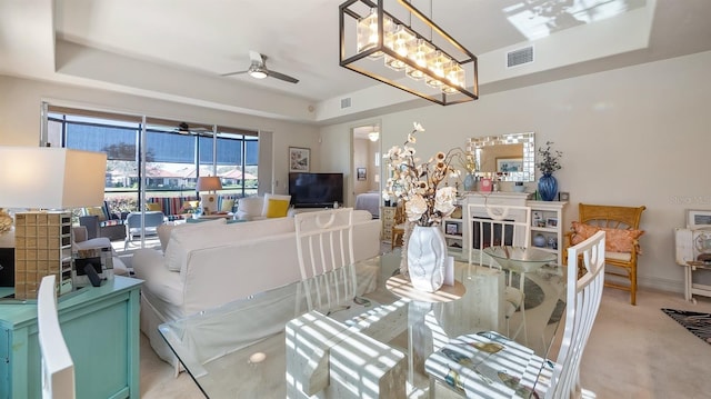 dining room featuring ceiling fan with notable chandelier, a raised ceiling, and visible vents