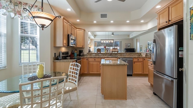 kitchen with visible vents, a kitchen island, appliances with stainless steel finishes, a peninsula, and a tray ceiling