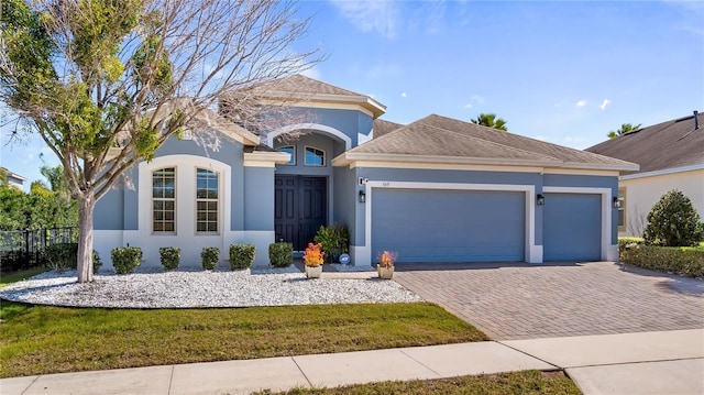 single story home featuring a garage, a shingled roof, fence, decorative driveway, and stucco siding