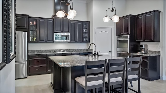 kitchen with a breakfast bar area, appliances with stainless steel finishes, glass insert cabinets, a sink, and light stone countertops