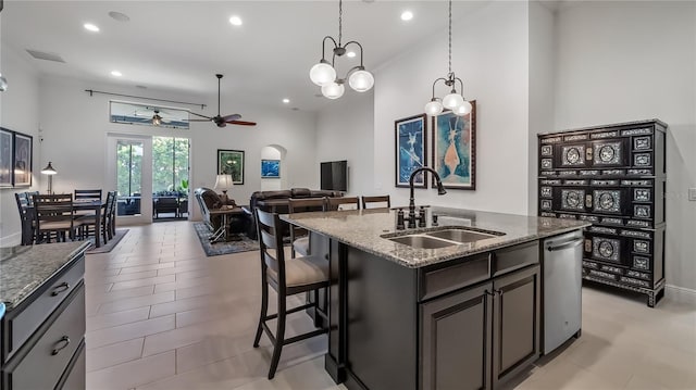 kitchen featuring stainless steel dishwasher, visible vents, dark stone counters, and a sink