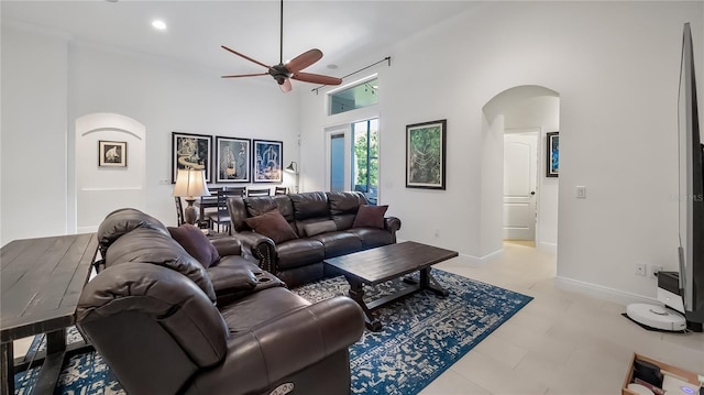 living room featuring arched walkways, baseboards, a towering ceiling, ceiling fan, and recessed lighting