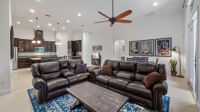 living area with arched walkways, visible vents, a towering ceiling, and recessed lighting