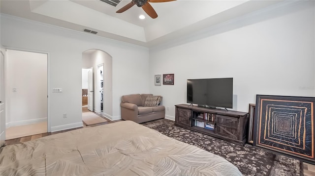 bedroom with arched walkways, baseboards, visible vents, and a tray ceiling