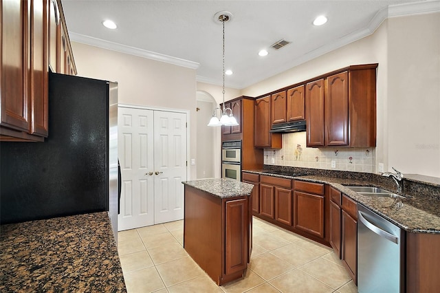 kitchen featuring stainless steel appliances, visible vents, decorative backsplash, a sink, and under cabinet range hood