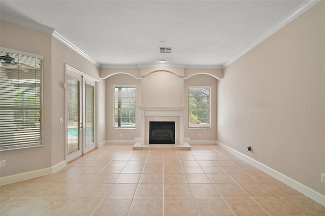 unfurnished living room with crown molding, light tile patterned floors, visible vents, a tiled fireplace, and a textured ceiling