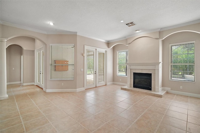 unfurnished living room featuring a textured ceiling, light tile patterned flooring, a fireplace, visible vents, and ornamental molding