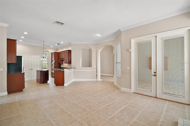 kitchen with arched walkways, light tile patterned flooring, visible vents, ornamental molding, and decorative columns