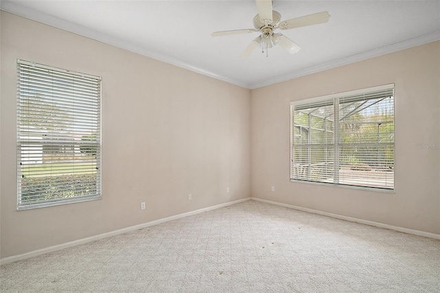 carpeted empty room with baseboards, a ceiling fan, and crown molding